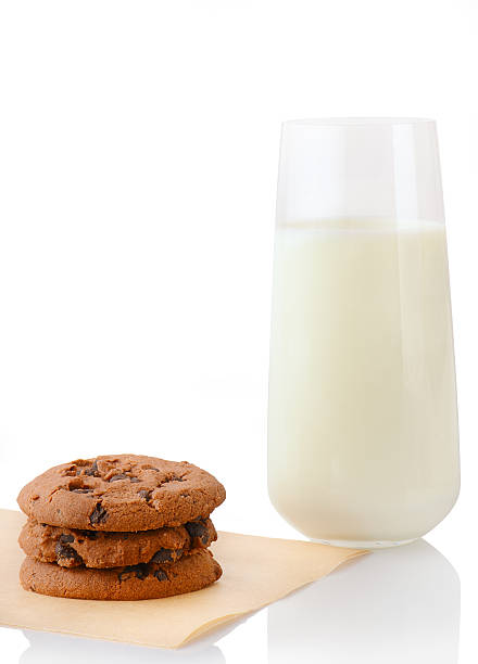 Chocolate chip cookies on baking paper and glass of milk