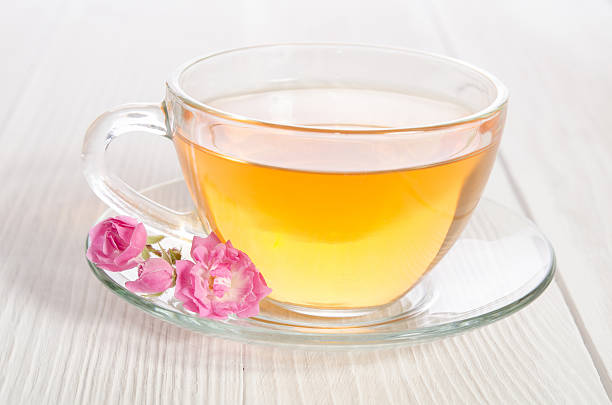 istock Glass cup of tea with rose on white wooden table 500800968
