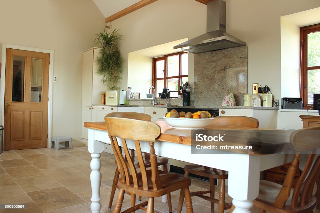 Country kitchen, granite worktop, gas range cooker, tiled floor, pine-table Image of a large and very spacious, real traditional country kitchen diner, with a dining area at one end of the room, furnished with a pine table and chairs, topped with a bowl of fresh fruit. The kitchen has Shaker style doors painted cream, with a beige patterned granite worktop surface, a double white Belfast sink / Butler sink, and a gas range cooker with a gas hob and stainless steel extractor hood. Chair Stock Photo Country kitchen, granite worktop, gas range cooker, tiled floor, pine-table Image of a large and very spacious, real traditional country kitchen diner, with a dining area at one end of the room, furnished with a pine table and chairs, topped with a bowl of fresh fruit. The kitchen has Shaker style doors painted cream, with a beige patterned granite worktop surface, a double white Belfast sink / Butler sink, and a gas range cooker with a gas hob and stainless steel extractor hood. Chair Stock Photo