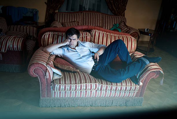 istock man lying on sofa and watching TV at night 500805055