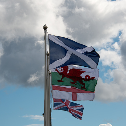 Flag of Wales waving atop of its pole against a blue sky.