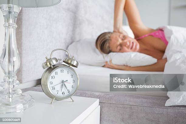 Pretty Blonde Covering Her Ears From The Alarm Clock Noise Stock Photo - Download Image Now