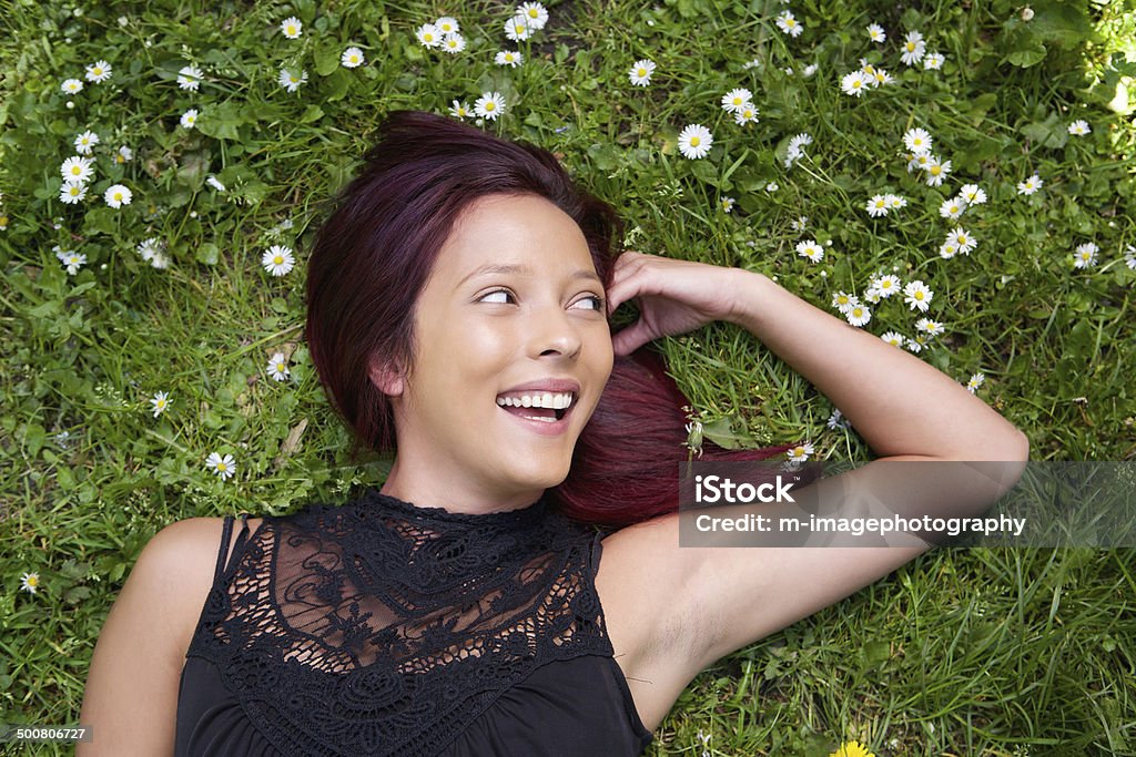 Attractive young woman lying on grass Portrait of an attractive young woman lying on grass and smiling 20-29 Years Stock Photo