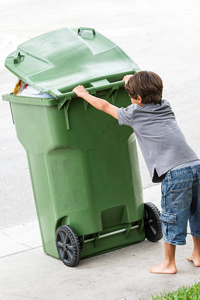 istock Child moving a wheeled trash can 500808281