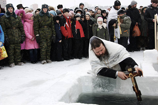 Novosibirsk, Russia - January 19, 2009: Russian people celebrate Epiphany (Holy Baptism). The priest dips the Orthodox cross on the Russian tradition. After a speech of priests, adults and children swimming in the hole. The air temperature at that time in Russia could be minus 20-40 C