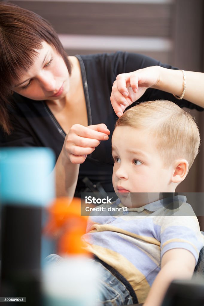 Hairdresser finishing boys haircut with hair setting Female hairdresser making finishing touches after boys haircut Adult Stock Photo