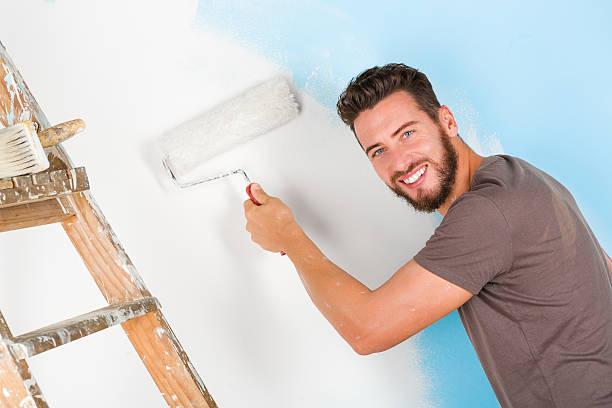 istock painter in paint splattered shirt painting a wall 500809070