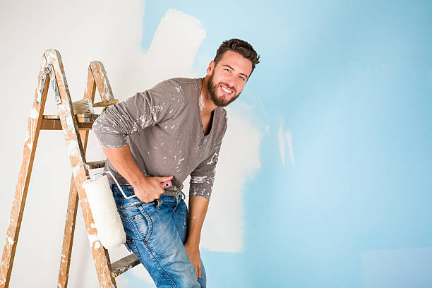istock painter in paint splattered shirt painting a wall 500810224