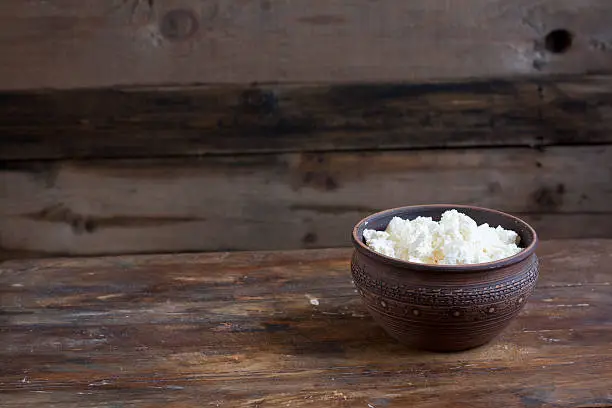 Culinary cottage cheese in a clay bowl on dark wooden table
