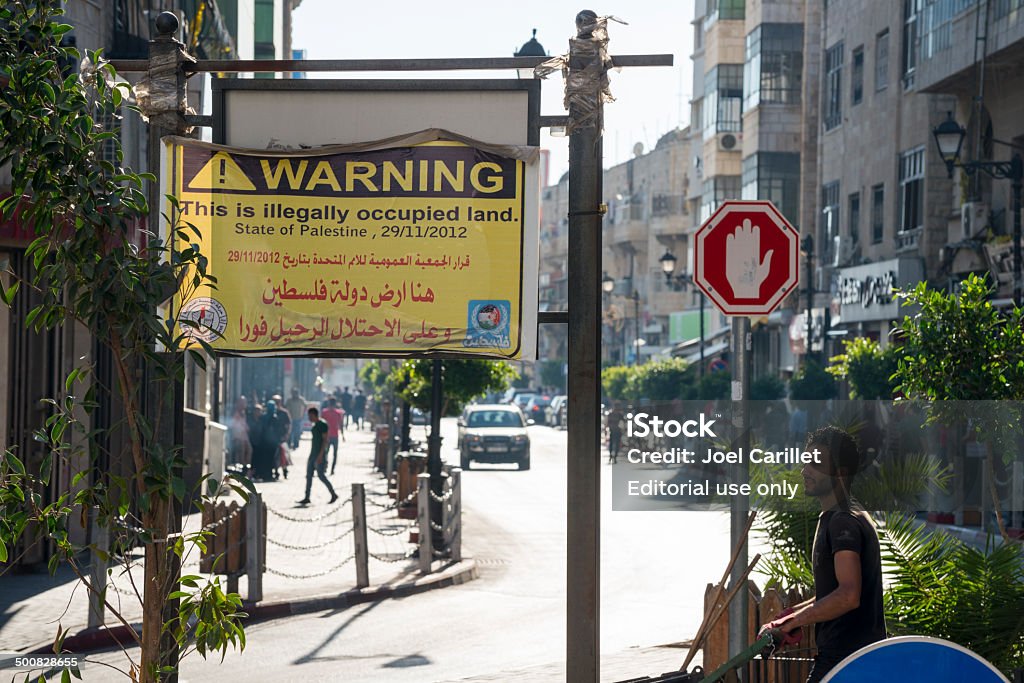 Illegally occupied land - Palestine Ramallah, West Bank, Palestinian Territories - July 22, 2013: A man walks toward a sign in the West Bank city of Ramallah which reads, "Warning: This is illegally occupied land". Ramallah Stock Photo