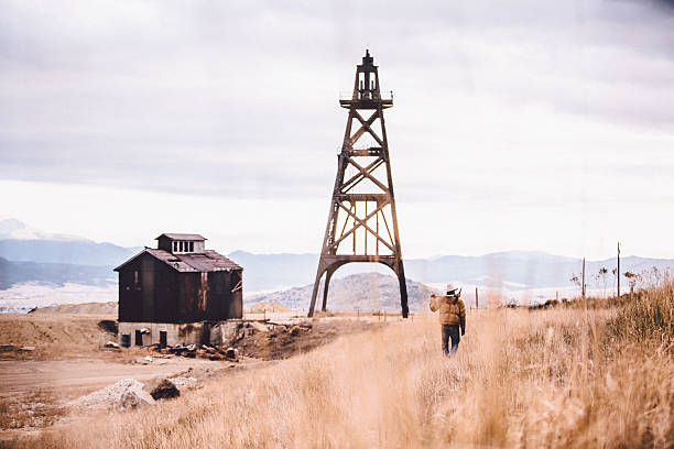 istock Man stands looking at barn and metal structure near mountains 500829483