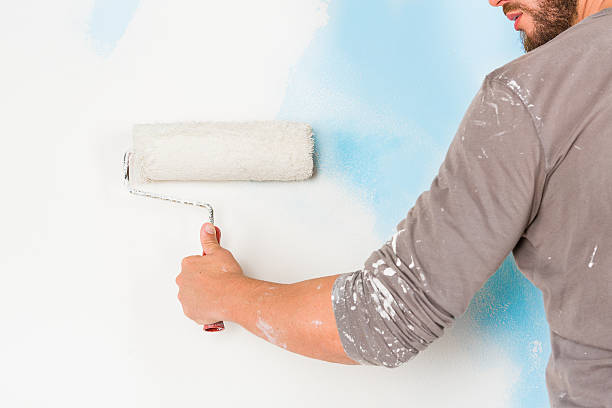 istock painter arm painting a wall with paint roller 500830956