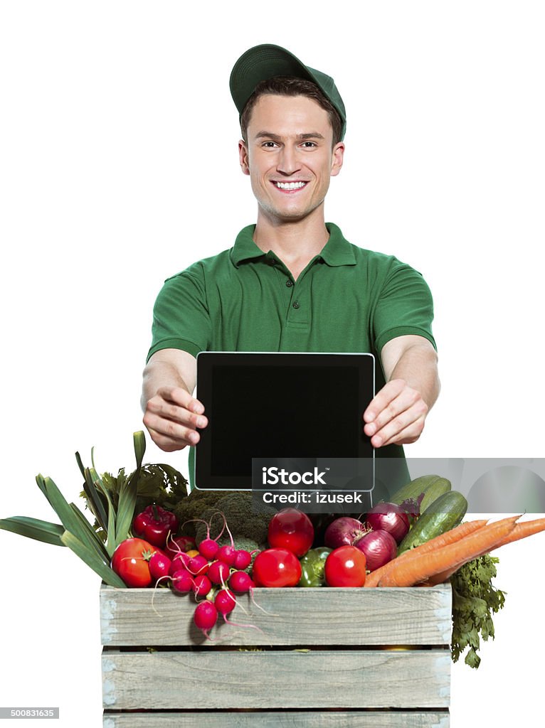 Delivery man with digital tablet Delivery man delivering box with organic food, holding digital tablet in hands and smiling at the camera. Studio shot, white background. Men Stock Photo
