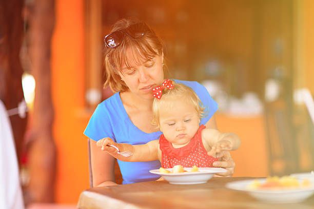 istock mother feeding little daughter in cafe 500833528