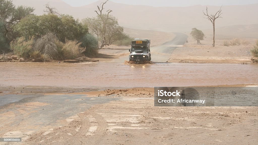 4x4 car crossing river during floods, Sossusvlei, Namibia When it is raining in the desert of Namibia it is difficult to cross the rivers. 4x4 cars are necessary on these roads. Africa Stock Photo