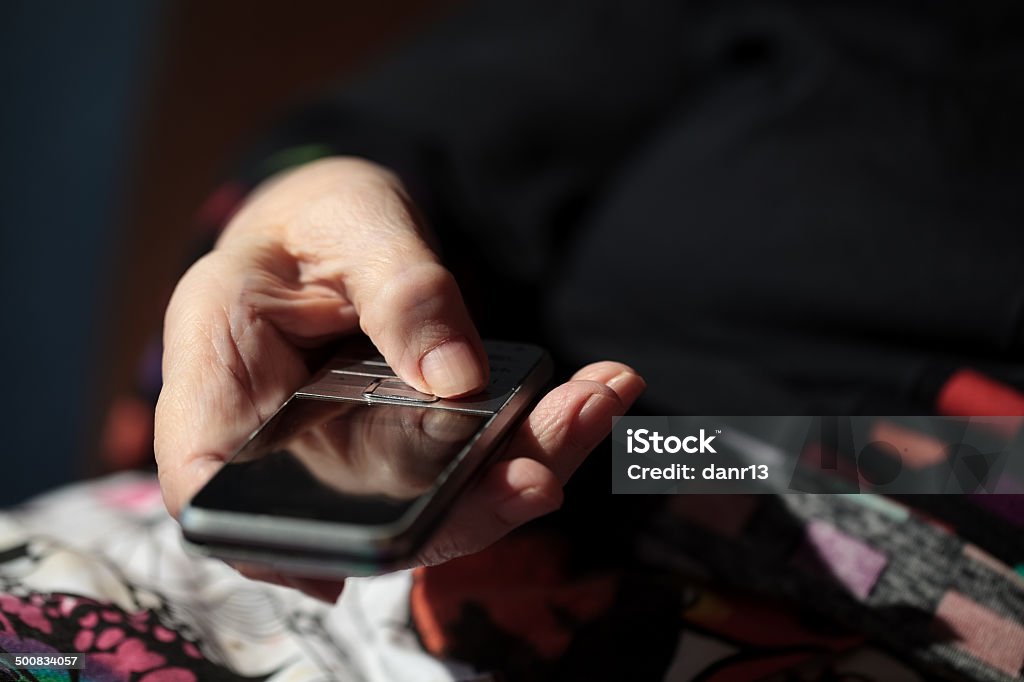 Old woman is going to dial a number on her Close-up shot of elderly womans hands holding a cell phone. She is going to dial a number Active Seniors Stock Photo