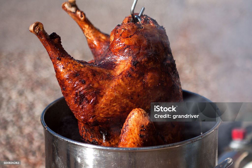 Deep Fried Turkey Hot fresh and delicious turkey being removed from a deep fat fryer after being cooked for a holiday celebration. Turkey Meat Stock Photo