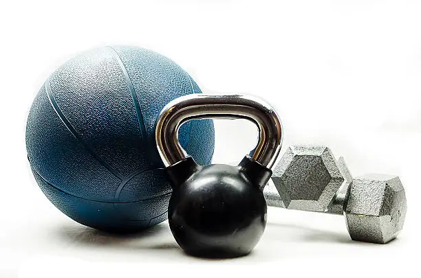 Black and silver kettlebell, blue medicine ball, and silver dumbbells