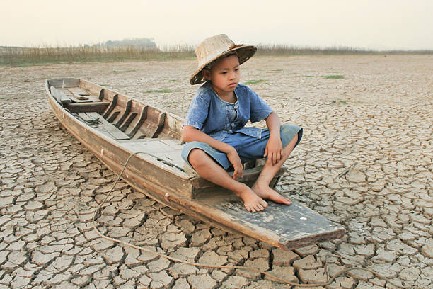 istock Choldren and wooden boat on cracked earth 500837682