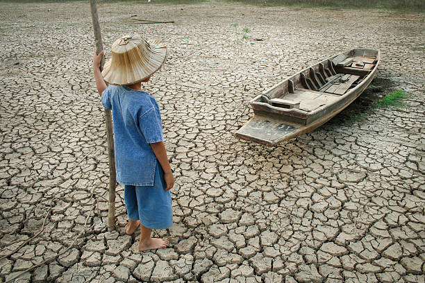 Children and climate change Children standing near the wooden boat on cracked earth. Metaphor for Global warming and Climate change. drought stock pictures, royalty-free photos & images