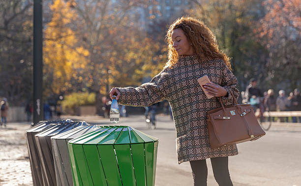 istock Woman on the street throwing a bottle into trash bin 500839038