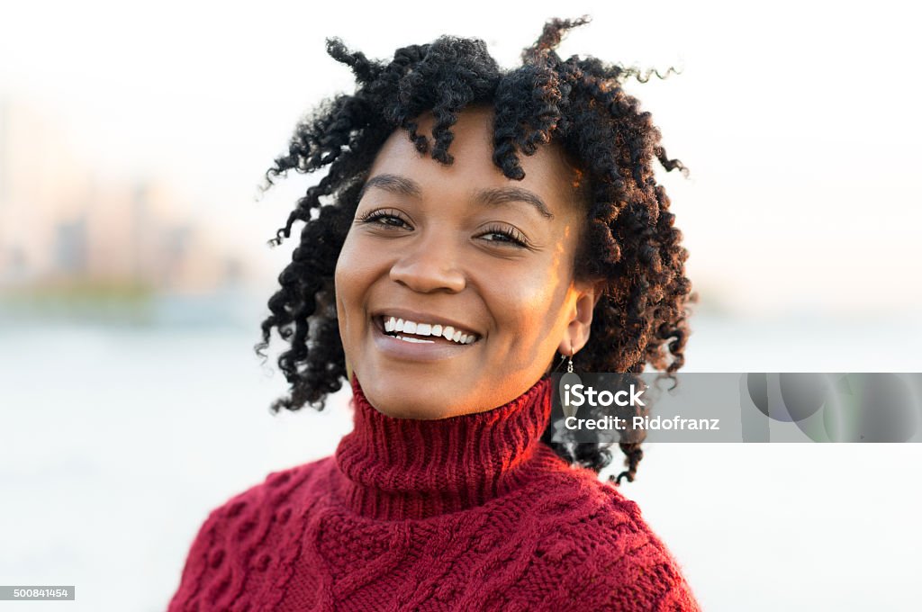 Smiling happy woman Close up portrait of an african woman standing at river side during sunset. Portrait of happy young african looking at camera. Smiling african woman posing for camera outdoor. 20-29 Years Stock Photo