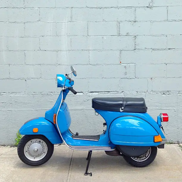 Blue motor scooter parked on the sidewalk