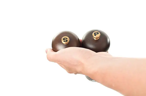 Photo of Asian male hand holding wooden salt and pepper shakers