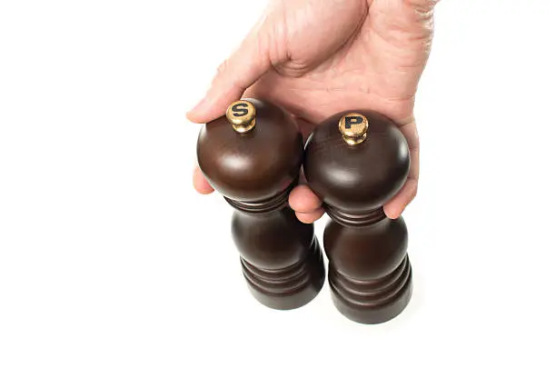 Photo of Asian male hand holding wooden salt and pepper shakers