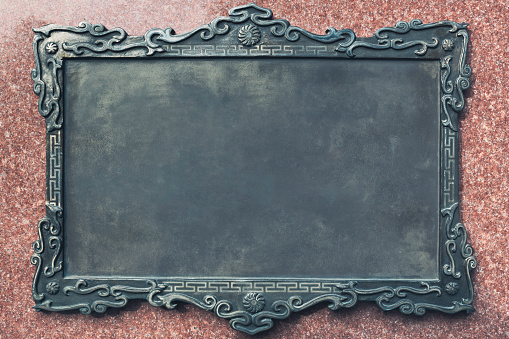 Closeup photo of an antique blank metal plaque on granite wall.