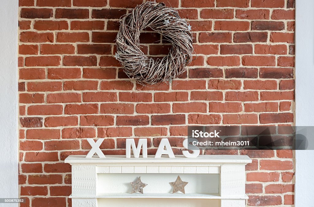 Decorated Christmas fireplace on a brick wall Decorated Christmas fireplace on a brick wall in a rustic home decorated with a wreath of twigs, stocking, stars and the letters Xmas to celebrate the holiday season Arts Culture and Entertainment Stock Photo
