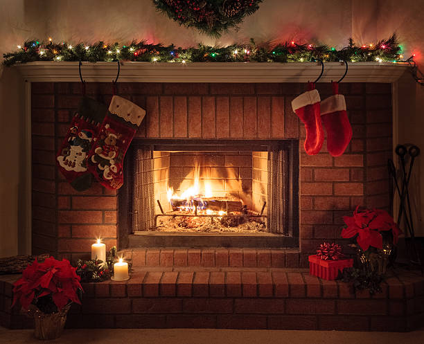 Christmas Fireplace, holiday decorations, cozy fire Cozy Christmas fireplace with Christmas lights, Christmas stockings hanging from the mantle, wreath, poinsettias, and other holiday decorations. red poinsettia vibrant color flower stock pictures, royalty-free photos & images