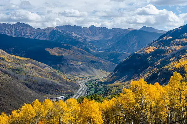 Wide angle view of I-70 winding it's way through the Vail Pass in the Colorado Rockies. Each Autumn, the Colorado Rocky Mountains create a dazzling and colorful display as the Aspens turn a brilliant yellow and glow against the mountains. In addition, their tall, vertical, trunks with white bark create a repetitive pattern under the foliage. Taken in Vail, Colorado on the summit of Vail Mountain.