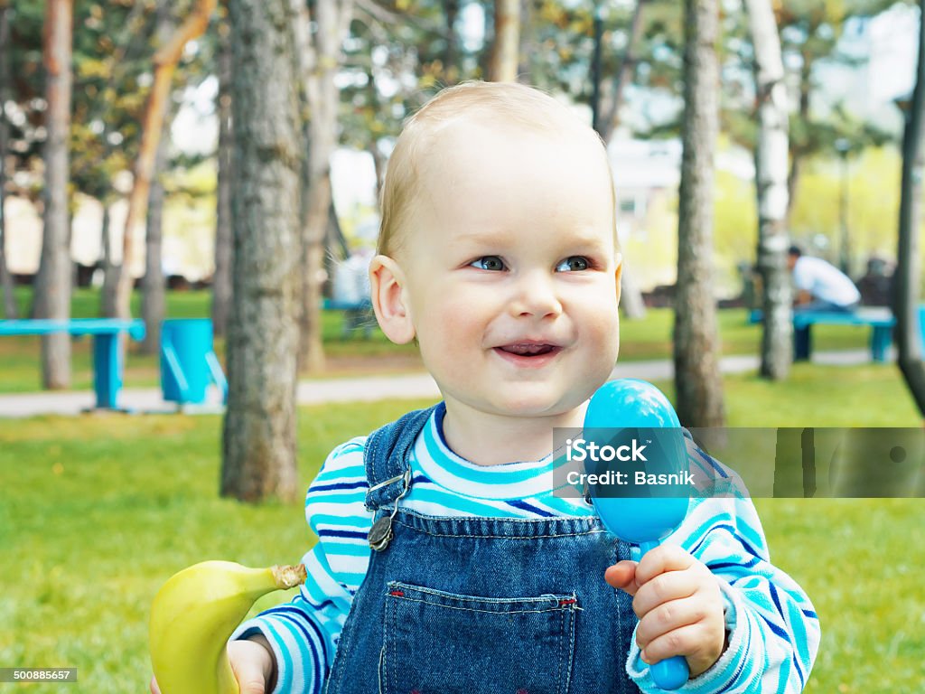 Baby with banana Portrait of nice caucasian baby boy holding fresh banana in summer outdoors Awe Stock Photo