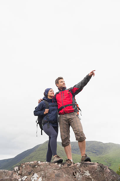 istock Couple standing on rock looking up at the mountains 500886275