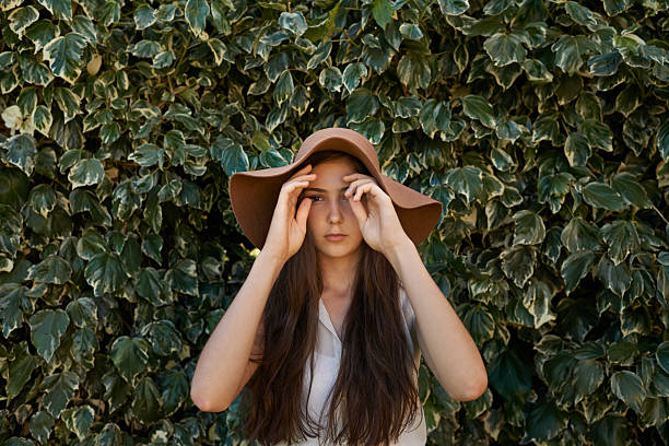 Cropped shot of a pretty teenage girl standing in front of a large hedgehttp://195.154.178.81/DATA/i_collage/pi/shoots/783557.jpg