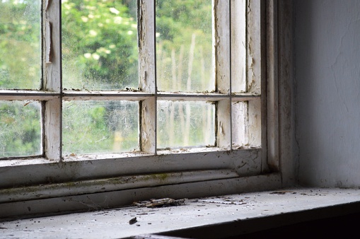 An old window sill with a dirty window and worn surroundings