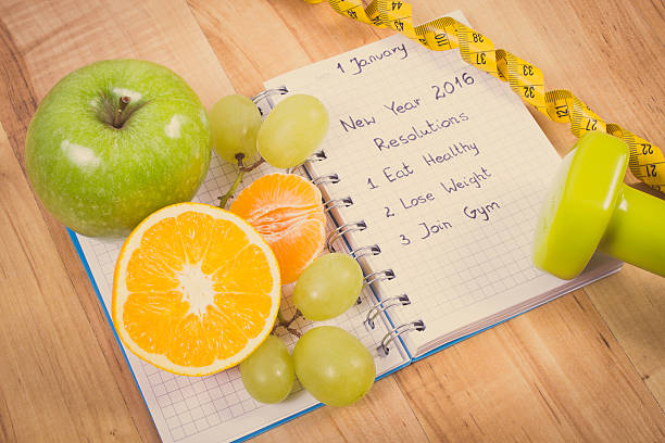 新しい年の解決の文書には、ノートパソコンやフルーツ、ダンベル、センチメートル - dieting planning calendar event ストックフォトと画像