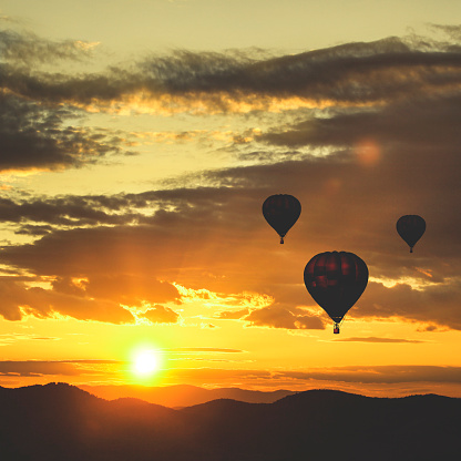 Three balloons flying during a beautiful sunset