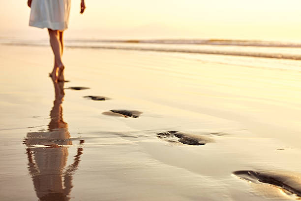istock Low section woman leaving footprints while walking on wet beach 500905406