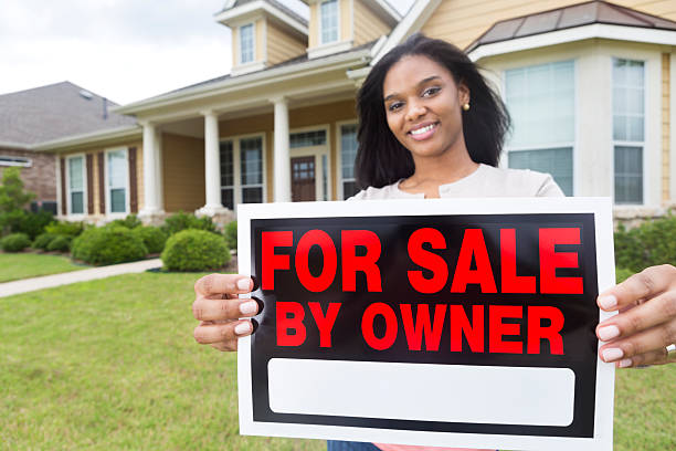 African American homeowner putting ""for sale"" sing in front yard African American homeowner putting "for sale" sing in front yard  house for sale by owner stock pictures, royalty-free photos & images