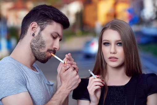 horizontal shot of urban couple smoking from their cigarettes, having cool attitude.head and shoulders, casual clothes.