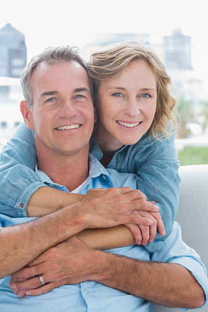 istock Happy woman hugging her husband on the couch from behind 500924749