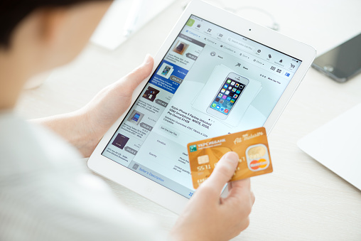 Kiev, Ukraine - June 27, 2014: Person holding a credit card and trying to buy a new Apple iPhone 5 with eBay application on a brand new Apple iPad Air. eBay is the worldwide online auction and shopping website, founded in September 3, 1995.