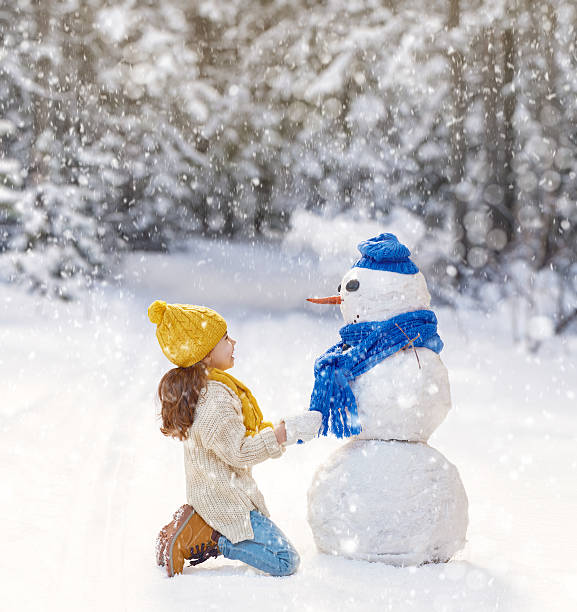 istock girl playing with a snowman 500928288