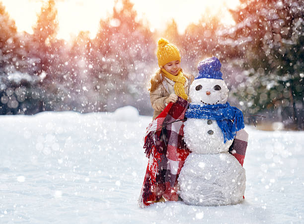 istock girl playing with a snowman 500928560