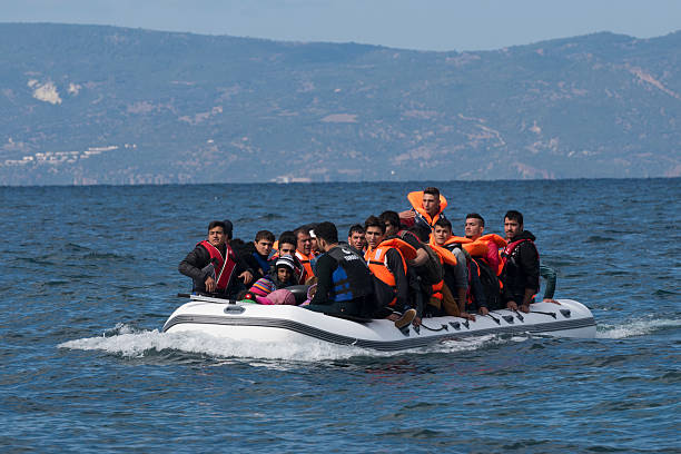 Migrants in inflatable boat between Greece and Turkey Lesbos, Greece - October 25, 2015: An inflatable boat filled with refugees and other migrants approaches the north coast of the Greek island of Lesbos. Turkey is visible in the background. More than 500,000 migrants have crossed by boat from Turkey to the Greek islands so far in 2015. immigrant stock pictures, royalty-free photos & images