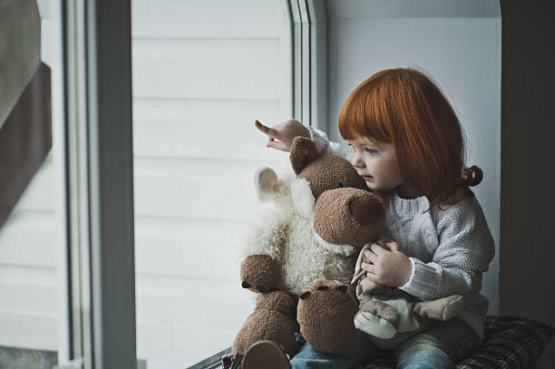 istock Girl with a toy sitting on the windowsill 500936392