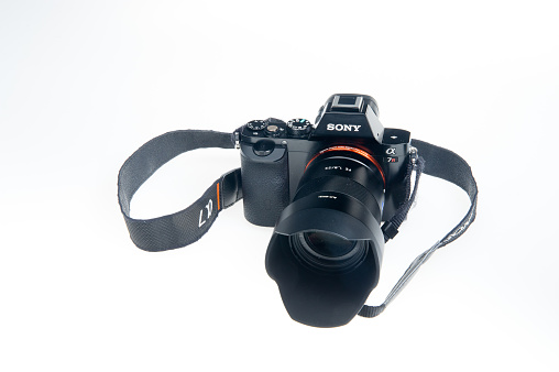 Bayreuth, Bavaria, Germany - December 12th, 2015: Sony mirrorless Camera Alpha 7R with 1.8 55 Emount lens and strap at white background. It´s a used camera with full frame sensor and 36.4 mega pix