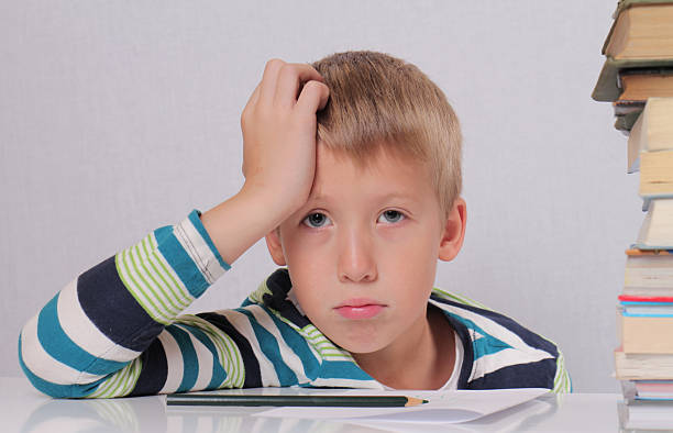 istock Cute tied eight years old school boy  doing homework 500939142